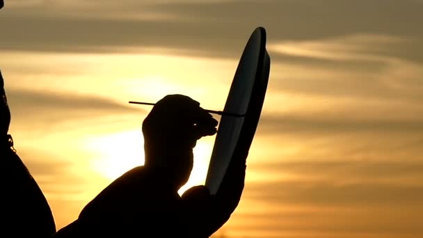 Silhouette of a Person Paints on a Plate Against a Beautiful Sky, Sunlight Beautifully Penetrating Into the Frame in Slow Motion — Stock Video