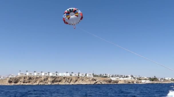 Barevný padák s parašutista letí po motorový člun, pevné s lanem, v létě — Stock video
