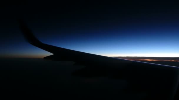 Ala del avión visto a través de una ventana con impresionante paisaje nublado en la noche — Vídeo de stock