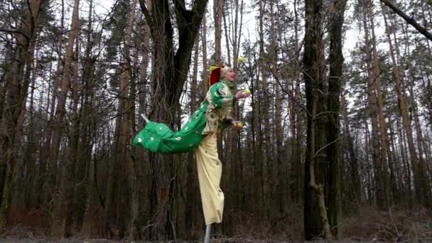 Grappige Clown springt en danst op één Stilt in een bos in Slow Motion — Stockvideo