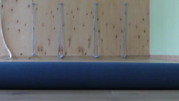 Молодой человек закатывает коврик для йоги в тренажерный зал в медленном движении — стоковое видео