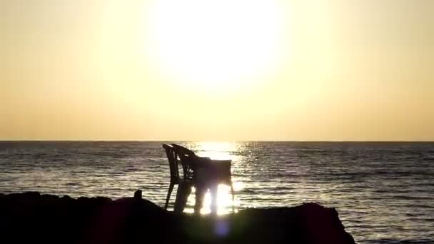 Két szék áll egy sziklás tengerpart, a Vörös-tengerre a naplemente tavasszal — Stock videók