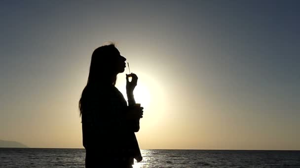 Slim Girl faz pequenas bolhas de sabão em um litoral ao pôr do sol em câmera lenta — Vídeo de Stock