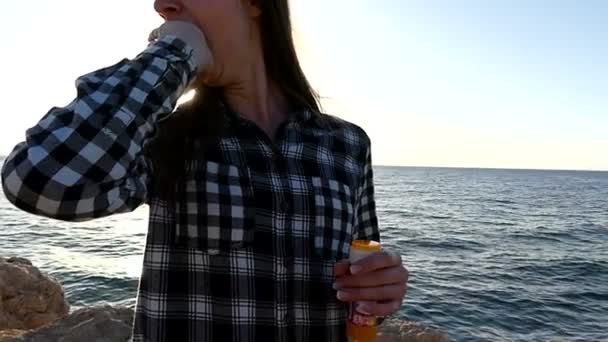 Νεαρή γυναίκα είναι χάσμημα με αστείο τρόπο στο ηλιοβασίλεμα σε ένα Seacoast σε Slo-Mo — Αρχείο Βίντεο