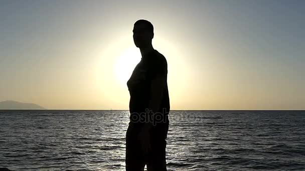 Молодой человек резвится и держит руку на своем бьющемся сердце на берегу моря в Сло-Мо — стоковое видео