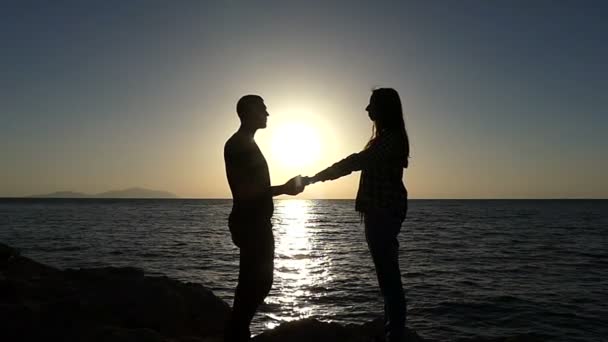 Joven abraza y besa a su novia en un mar al atardecer en Slo-Mo — Vídeos de Stock