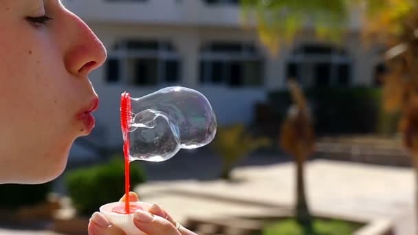 Jonge vrouw is maken talrijke zeepbellen met een rode zeep Wand Outdoors — Stockvideo