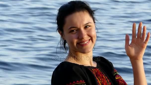 Glückliches Mädchen lächelt und winkt mit der Hand an einer Küste mit blauem Wasser in Ägypten — Stockvideo