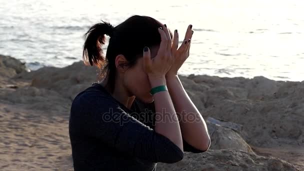 Genç kadın bir Yoga Mat gri spor kıyafetli bir Seabeach üzerinde oturan kulaklarını losyonları — Stok video