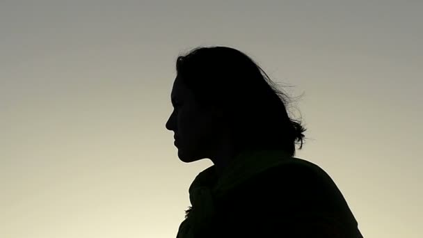 Mulher jovem coloca em seus óculos de sol pretos e balança a cabeça em um pôr do sol esplêndido — Vídeo de Stock