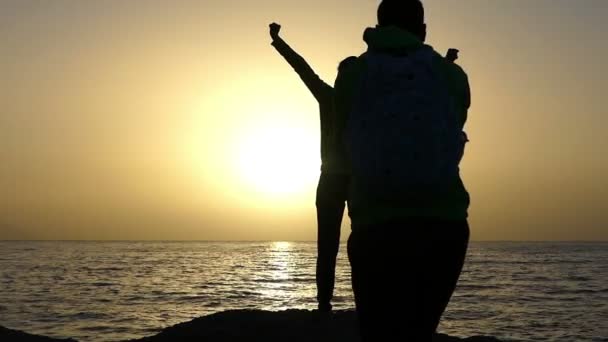 Glückliche junge Frau hebt die Fäuste und ein Mann filmt sie bei Sonnenuntergang mit einer Kamera — Stockvideo