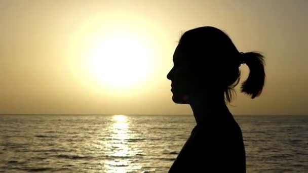Leuk meisje bidt in de christelijke traditie op een zee-strand bij zonsondergang in de zomer — Stockvideo
