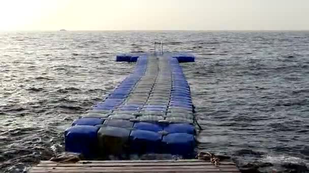 蓝色和白色塑料浮桥是摇曳像条蛇上红色海浪在晴朗的一天 — 图库视频影像
