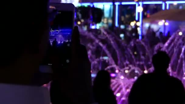 夜もライトアップされたカラフルな噴水で撮影の陽気な人々 — ストック動画