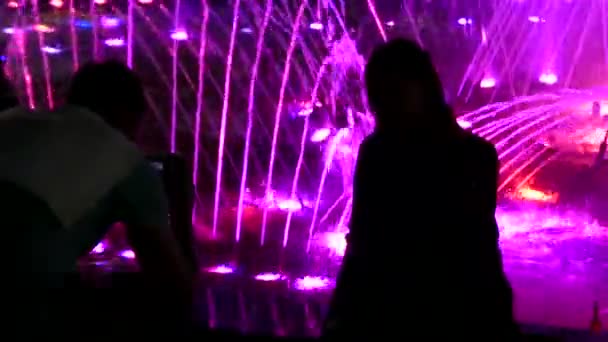 Fantastischer Brunnen mit bunten Wasserströmen und Menschen, die ihn schießen — Stockvideo