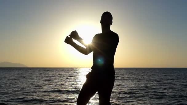 Молода людина танцях диско смішно чином на на березі моря, на заході сонця в уповільненому Русі — стокове відео