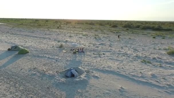 Tiro aéreo de tiendas de campaña y una sombrilla con gente en la costa de la isla de Dzharylhach — Vídeo de stock