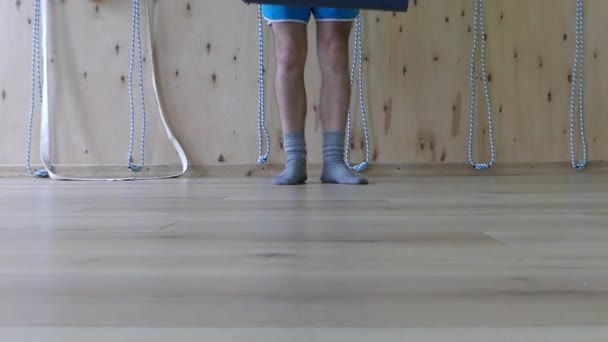 Junger Mann geht an die Wand, rollt eine Matte für Yoga aus und macht sich in slo -mo fertig — Stockvideo