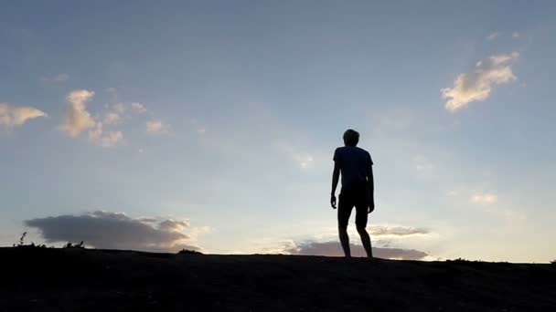 Hombre feliz salta alto y aplaude sus manos en una zona montañosa al atardecer en Slo-Mo — Vídeo de stock