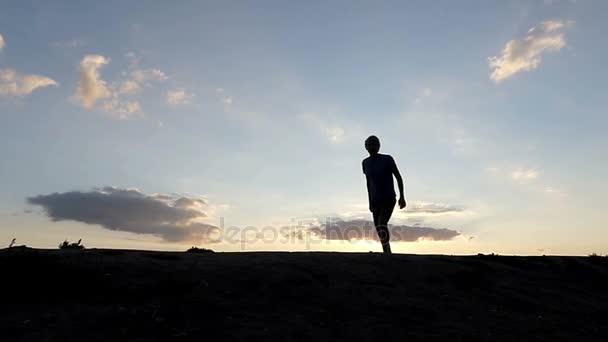 Ung Man hoppar högt och ler i ett bergigt område vid solnedgången i Slo-Mo — Stockvideo