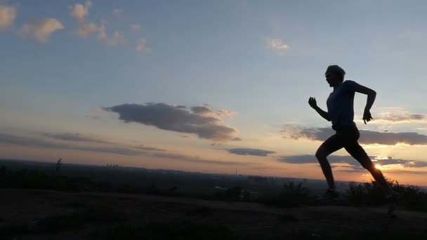 Atletisk Man körs snabbt i ett bergigt område vid solnedgången i Slo-Mo — Stockvideo