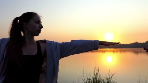 Δύο νέων γυναικών κάνει γιόγκα άσκηση στην Τράπεζα λίμνης υπέροχος στο ηλιοβασίλεμα — Αρχείο Βίντεο