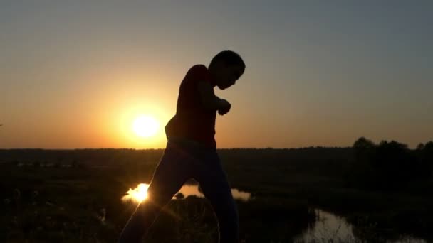 Спортивний хлопчик готує боксу удари на березі озера в Sunset восени в Slo-Mo — стокове відео