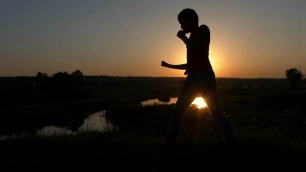Маленький хлопчик готує боксу удари на березі озера в Sunset восени - фокусування — стокове відео