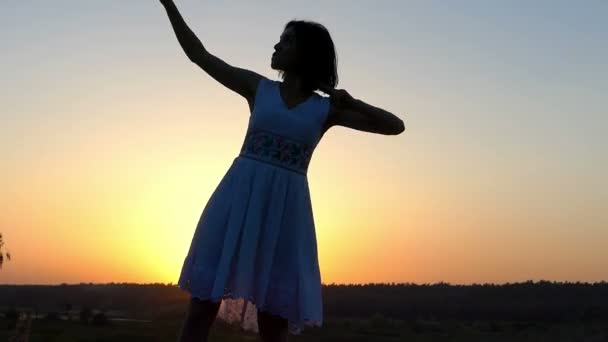 junge schlanke Frau tanzt bei Sonnenuntergang energisch in Tracht
