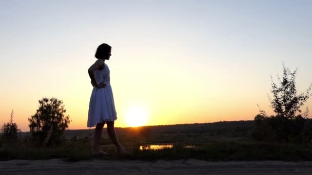 Молодая стройная женщина поднимает свою прямую ногу на великолепном закате в Сло-Мо — стоковое видео