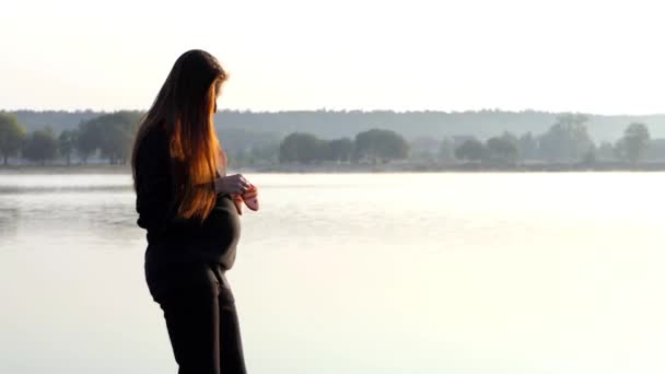 Μια ωραία γυναίκα έγκυος χορεύει με παντόφλες του μωρού κατά το ηλιοβασίλεμα το φθινόπωρο στην Slo-Mo — Αρχείο Βίντεο