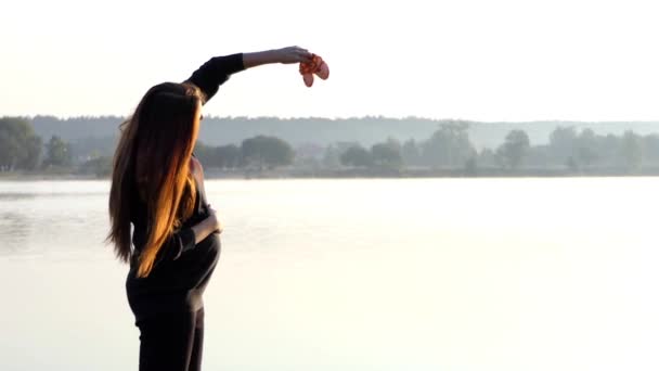 Una madre embarazada juega con zapatillas para su bebé al atardecer en otoño en Slo-Mo — Vídeo de stock