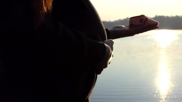 Беременная женщина стоит с тапочками для своего ребенка на рассвете осенью — стоковое видео