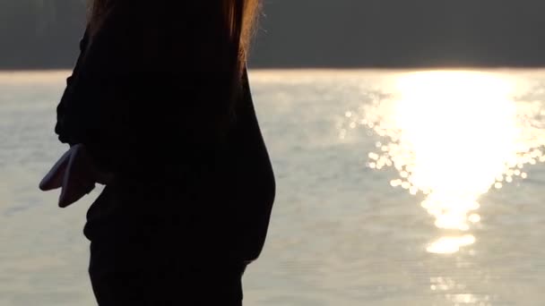 Eine schwangere Frau hält die Hausschuhe für ihr Baby bei Sonnenuntergang im Herbst — Stockvideo