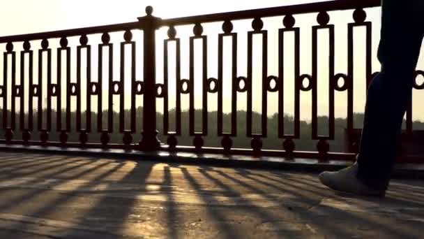 Les pieds masculins se déplacent le long d'un pont moderne à un magnifique coucher de soleil en été — Video