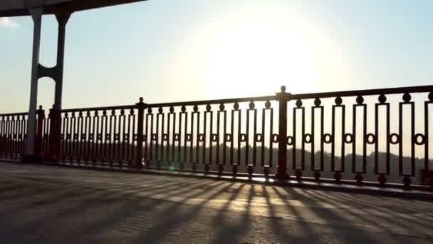 Młody człowiek biegnie wzdłuż nowoczesny most w belkach wspaniały zachód słońca w Slo-Mo — Wideo stockowe