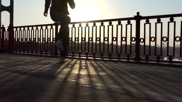 Молодой человек танцует джайв на современном мосту в лучах великолепного заката в Сло-Мо — стоковое видео