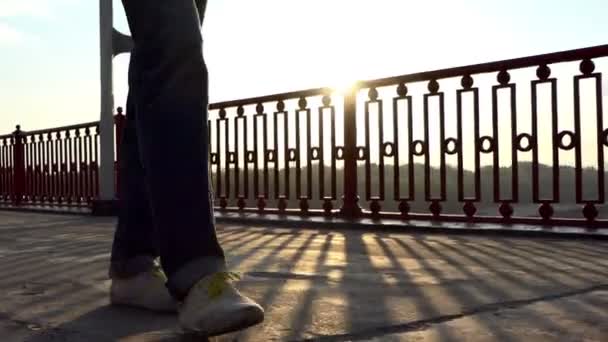 Leende Man går längs en Modern bro i balkar av fantastisk solnedgång i Slo-Mo — Stockvideo