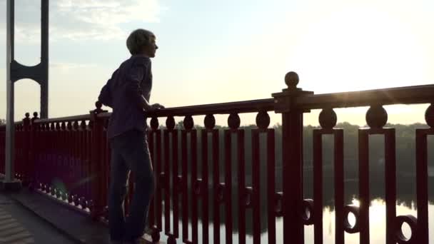 若い男ドニエプル川と笑顔とスローモーションの橋に沿って行くを見て — ストック動画