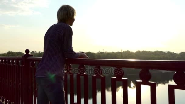 Un jeune homme souriant profite d'une vue sur la rivière Dnipro depuis le pont de Slo-Mo — Video