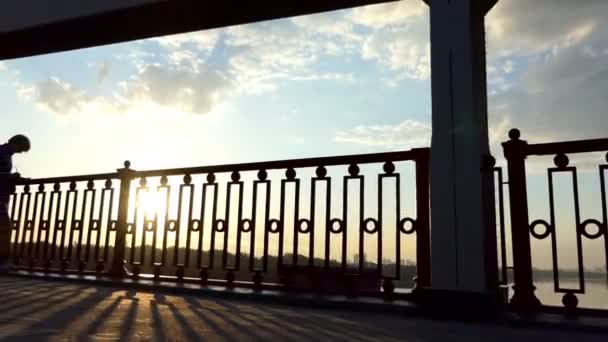 Joven pone sus ideas en un cuaderno en la orilla de un río al atardecer — Vídeo de stock