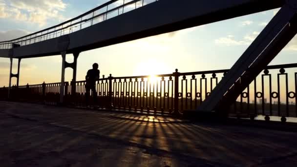 Genç adam rahatlatır, kahve içer ve bir gün batımı Slo-mo köprüdeki sahiptir — Stok video