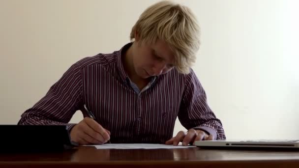 Jeune homme remplit un document, utilise sa calculatrice au bureau — Video