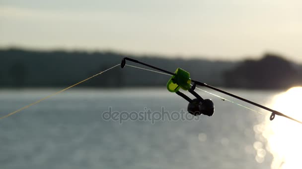 Grignoter au coucher du soleil à l'extrémité de la canne à pêche avec des cloches à l'extrémité . — Video