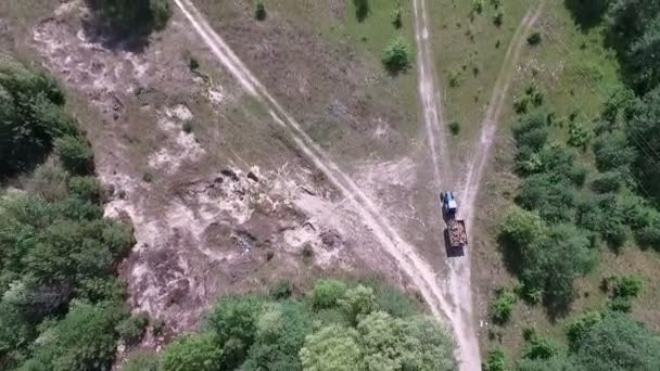 A tractor with a trailer of firewood is driving along the forest road. — Stock Video