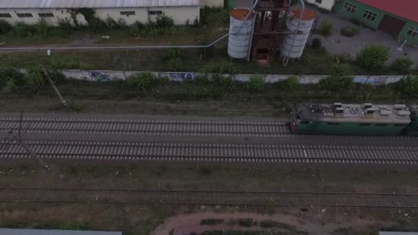 Vue aérienne d'un train de marchandises roulant lentement avec des bâtiments à proximité — Video