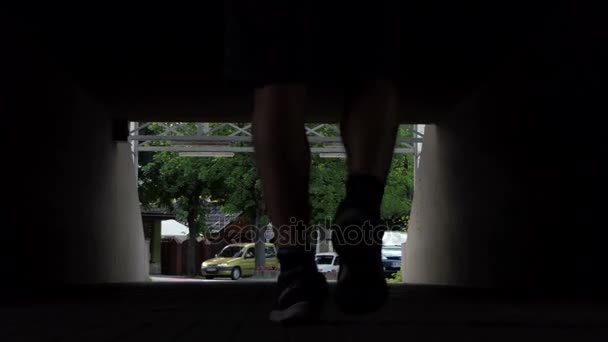 Jambes masculines en short et baskets passent par une traversée souterraine — Video