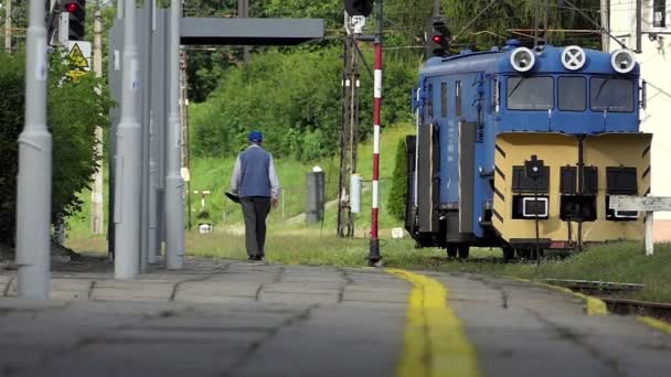 Een oude man in uniform gaat langs een spoorweg in de zomer in slo-mo — Stockvideo