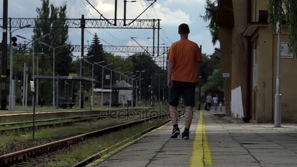 A young man goes away on a railroad platform in summer in slo-mo — Stock Video