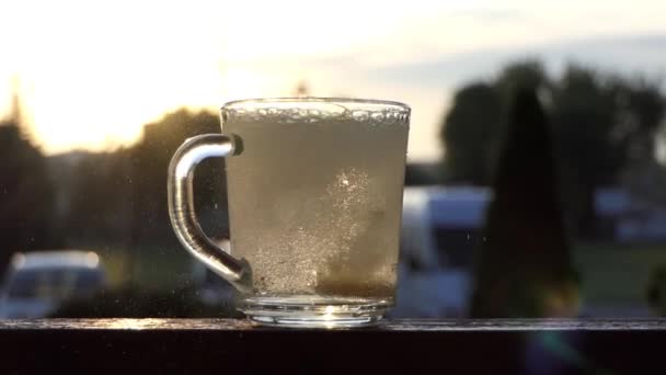 Um copo transparente de água de repente recebe algum comprimido. a fervura de partida de água — Vídeo de Stock